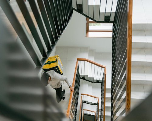 A person climbing stairs slowly carrying groceries
