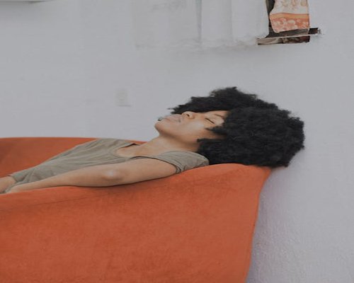 A person resting with eyes closed on a sofa